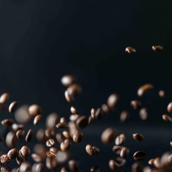 many flying coffee beans on black background